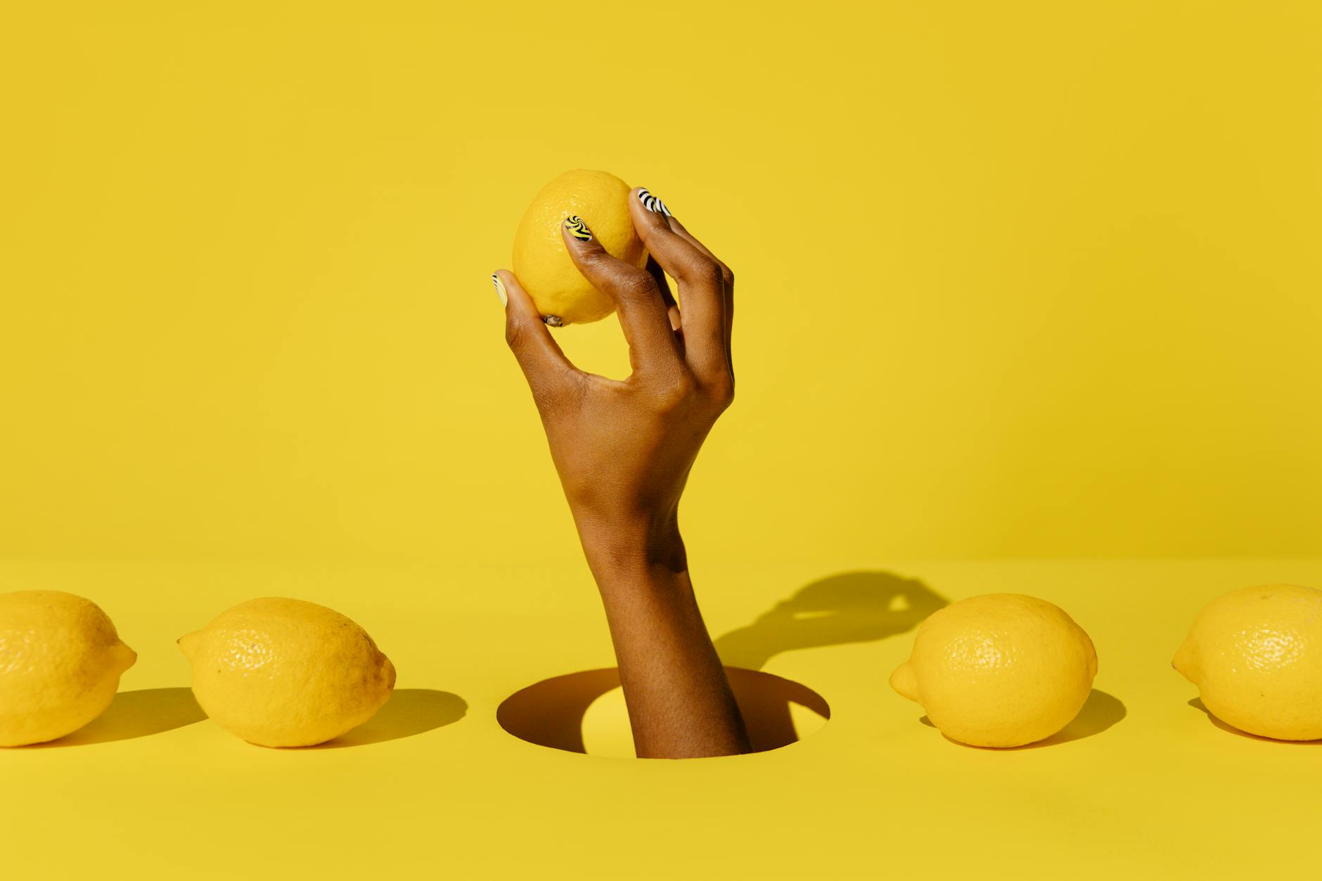 A hand holding a fresh lemon against a vivid yellow background, symbolizing renewal and fresh sensation after treatment
