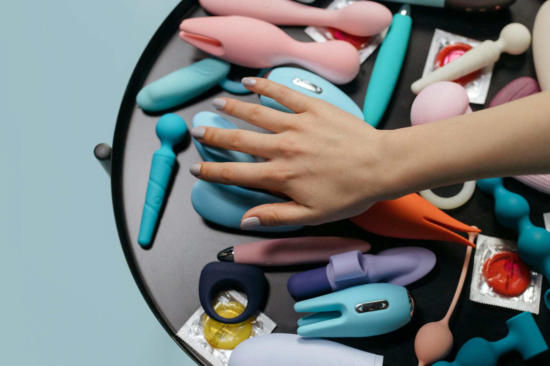 Hand selecting from a collection of colorful vibrators, representing the diversity of pleasure options available.