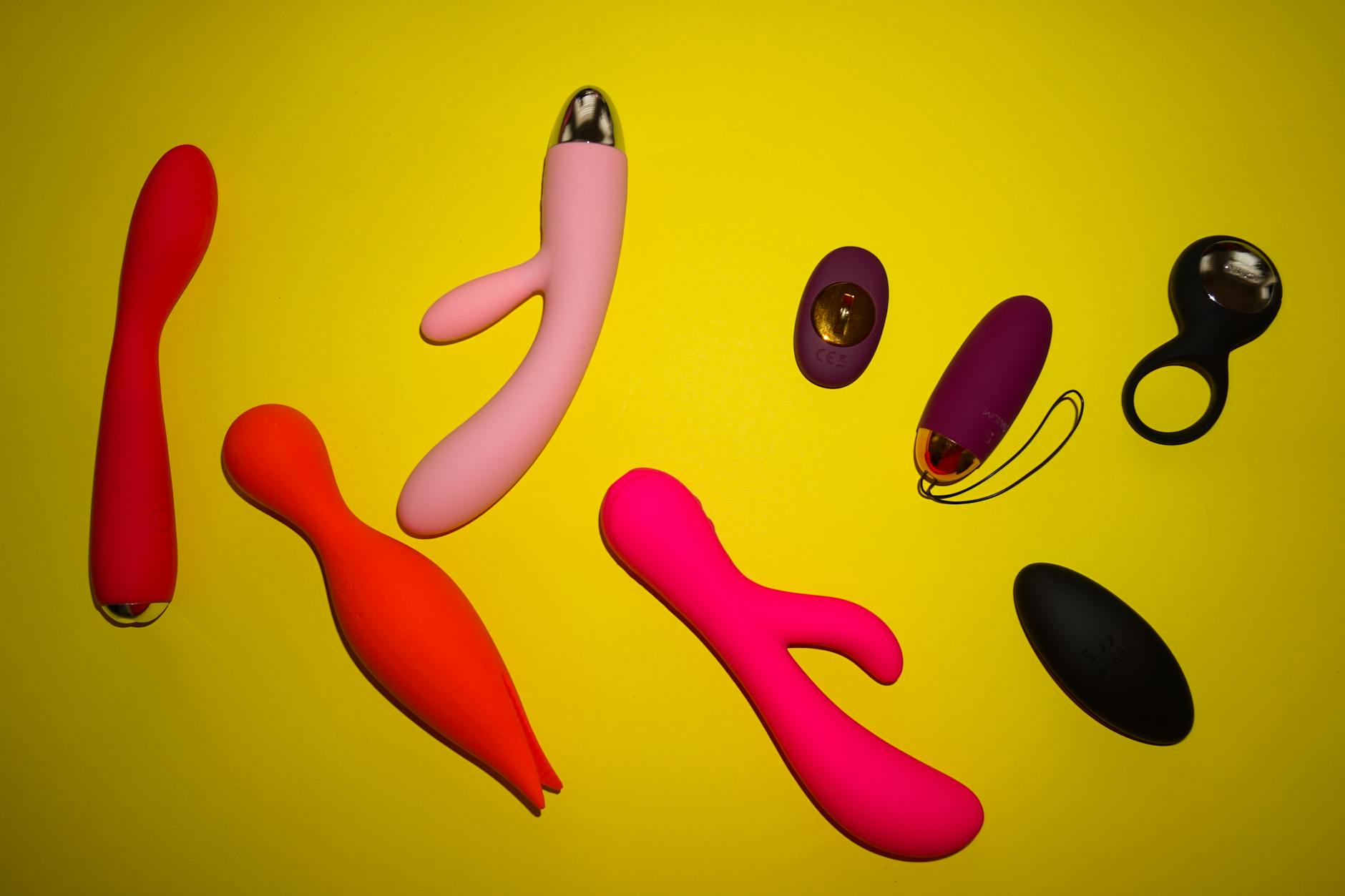 Arrangement of colorful lemon vibrators and sexual wellness toys on a bright yellow surface